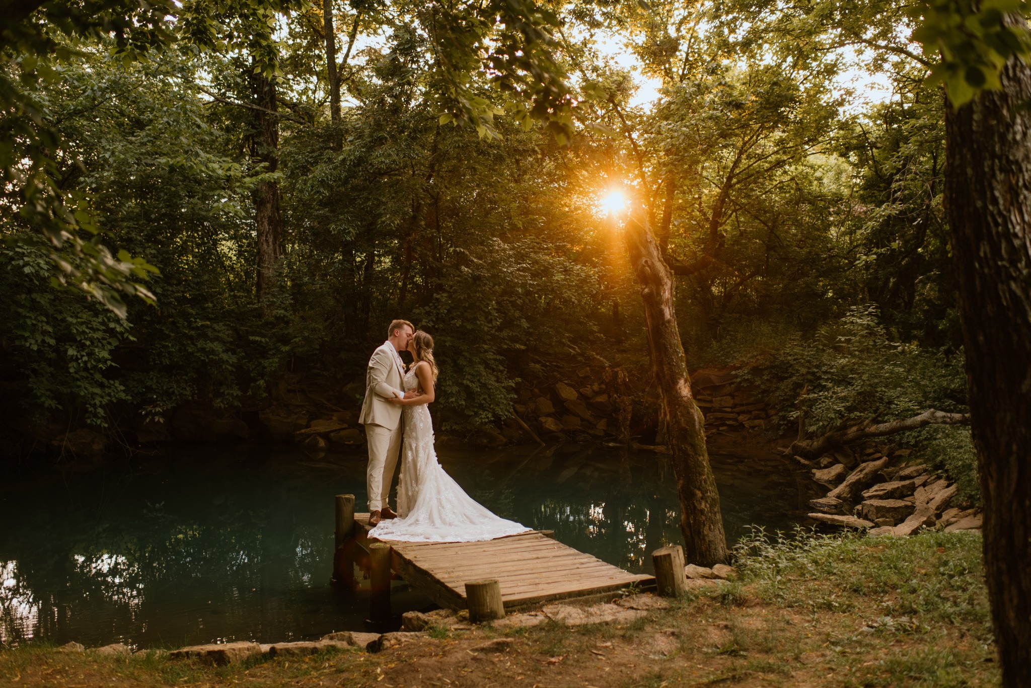 A newlywed couple on the dock beside the blue spring at sunset
