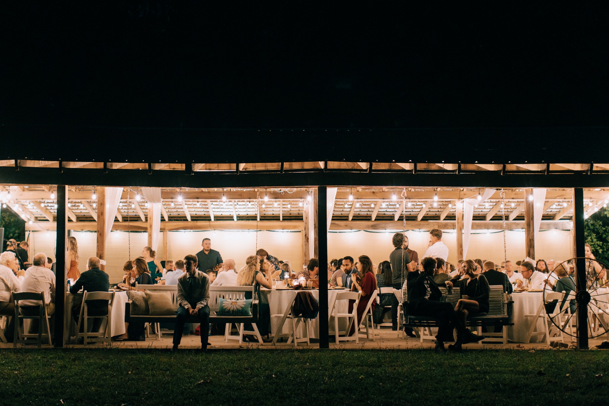 Guests gathered for an evening wedding reception beneath the pavilion