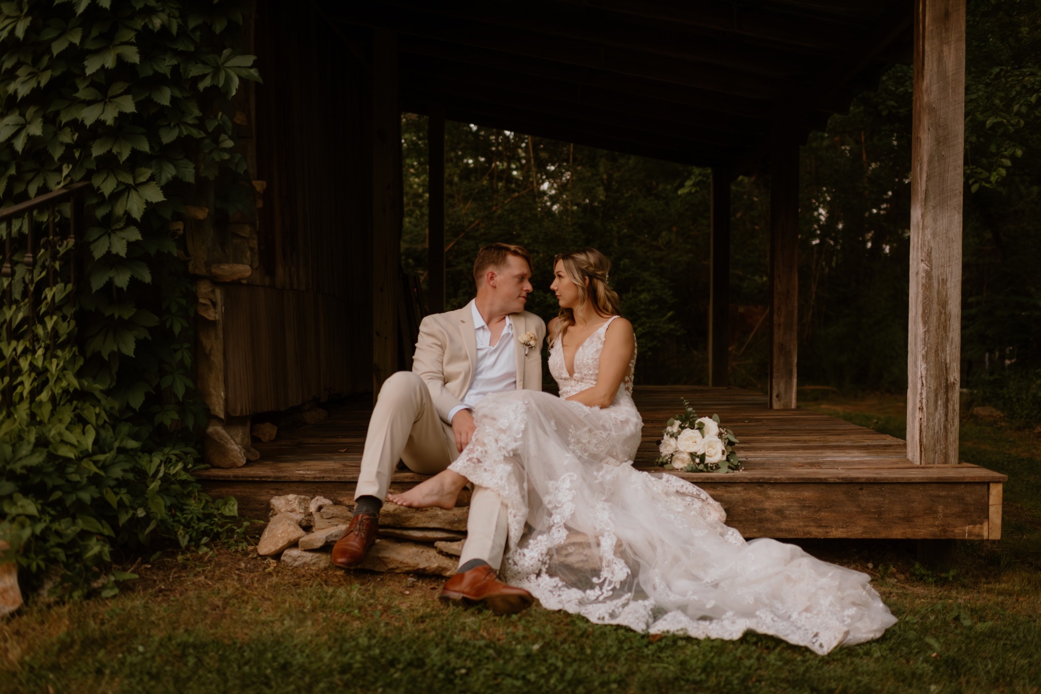 A newlywed couple seated on a rustic porch
