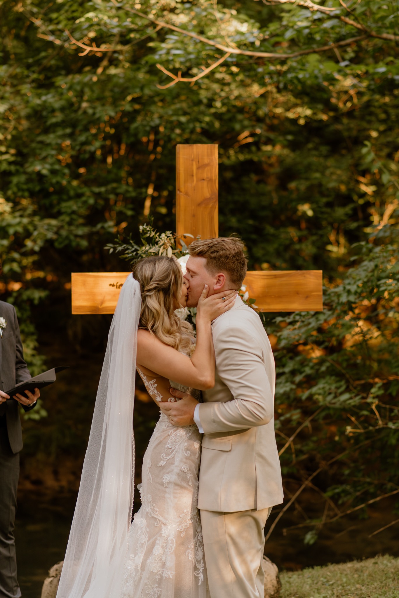 A ceremony kiss beneath a wooden cross