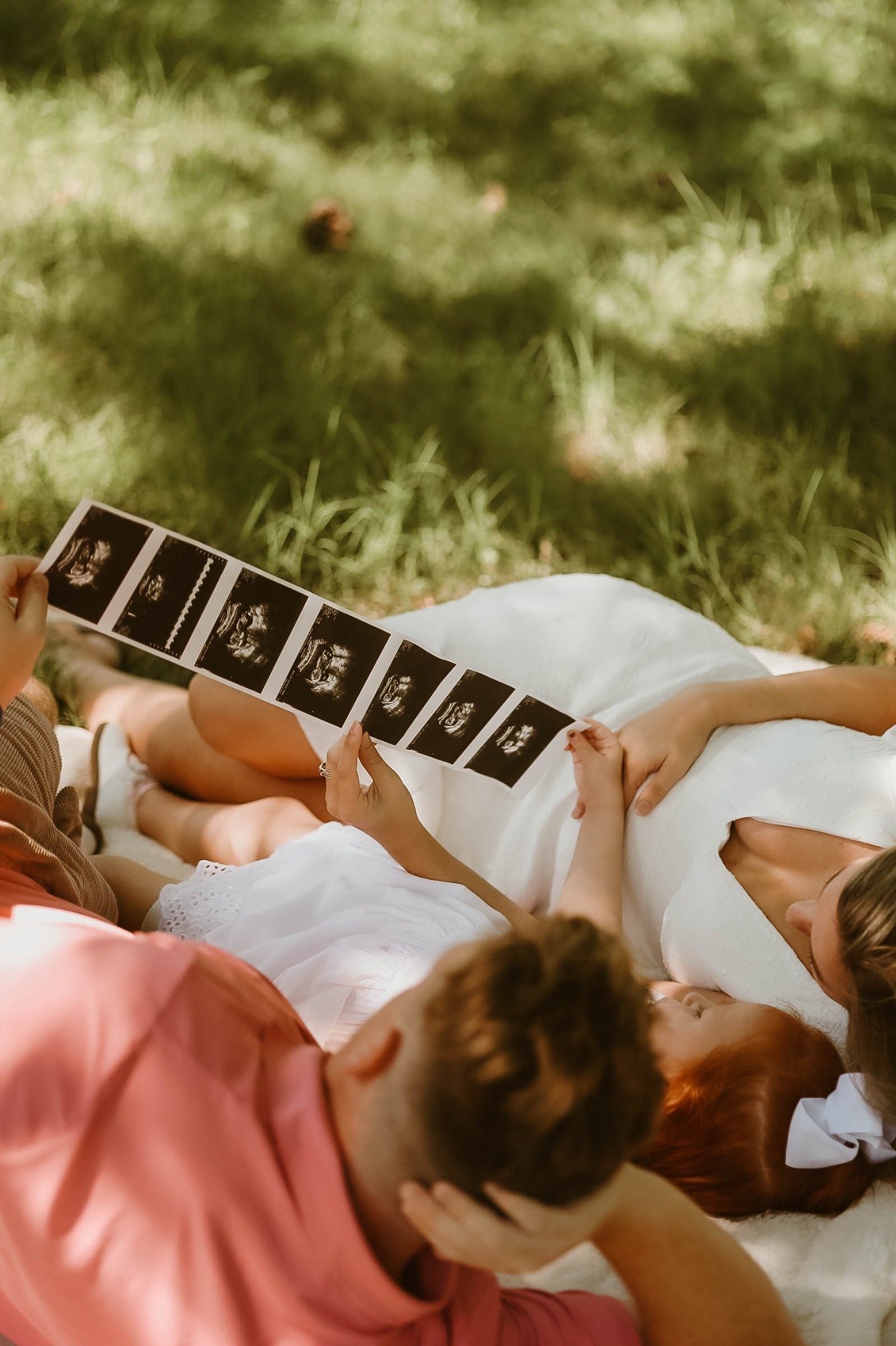 A family sharing ultrasound photographs in a sunlit field