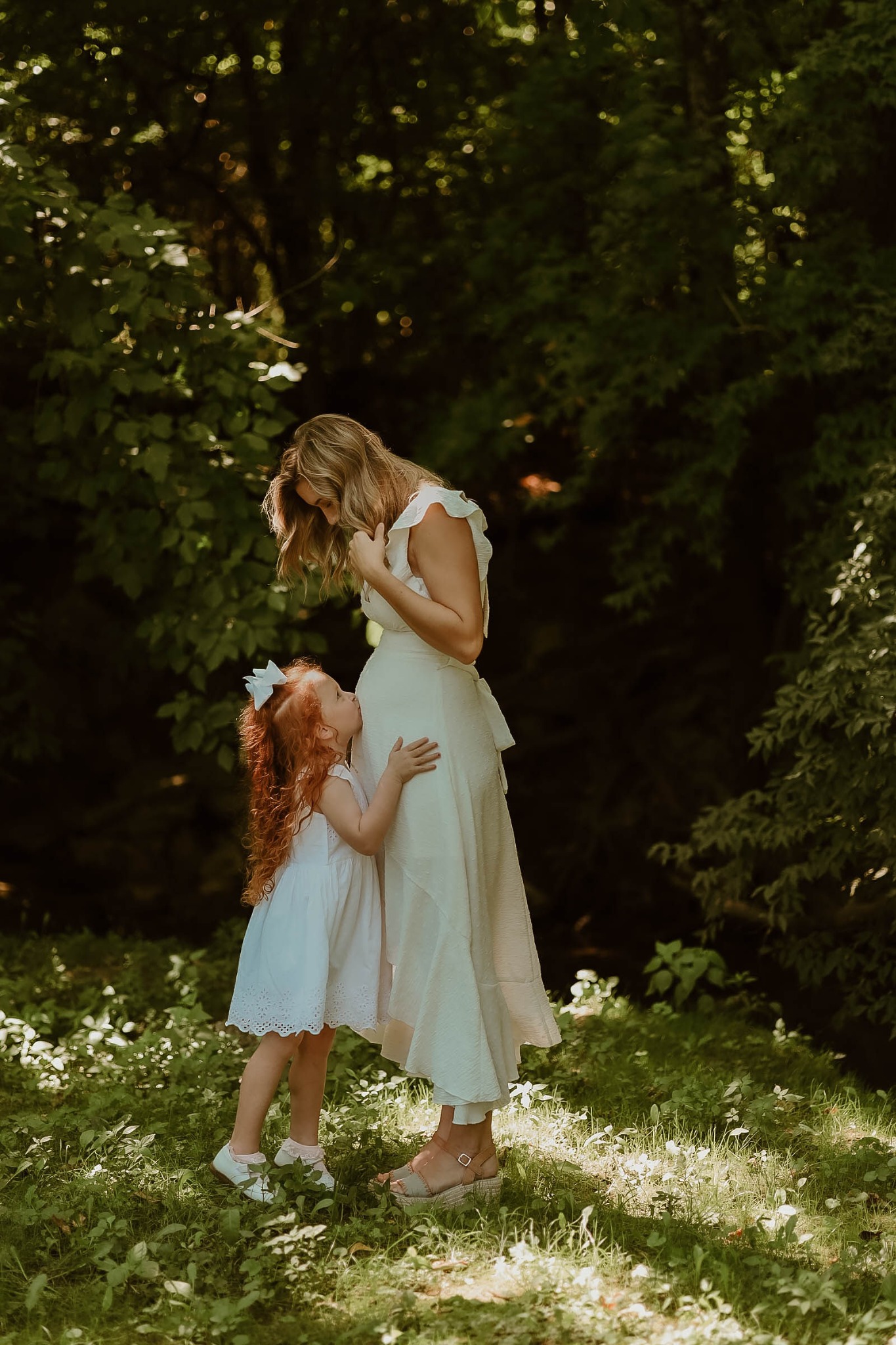 A mother and daughter sharing a quiet moment beneath the trees
